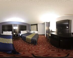 Spacious guest room with two beds, television, work desk, microwave, mini refrigerator, and patterned carpeting at Coratel Inn & Suites By Jasper Hastings.