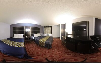 Spacious guest room with two beds, television, work desk, microwave, mini refrigerator, and patterned carpeting at Coratel Inn & Suites By Jasper Hastings.