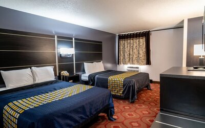 Guest room with two beds, patterned bedding, window, and dark wood furnishings at Coratel Inn & Suites By Jasper Hastings.
