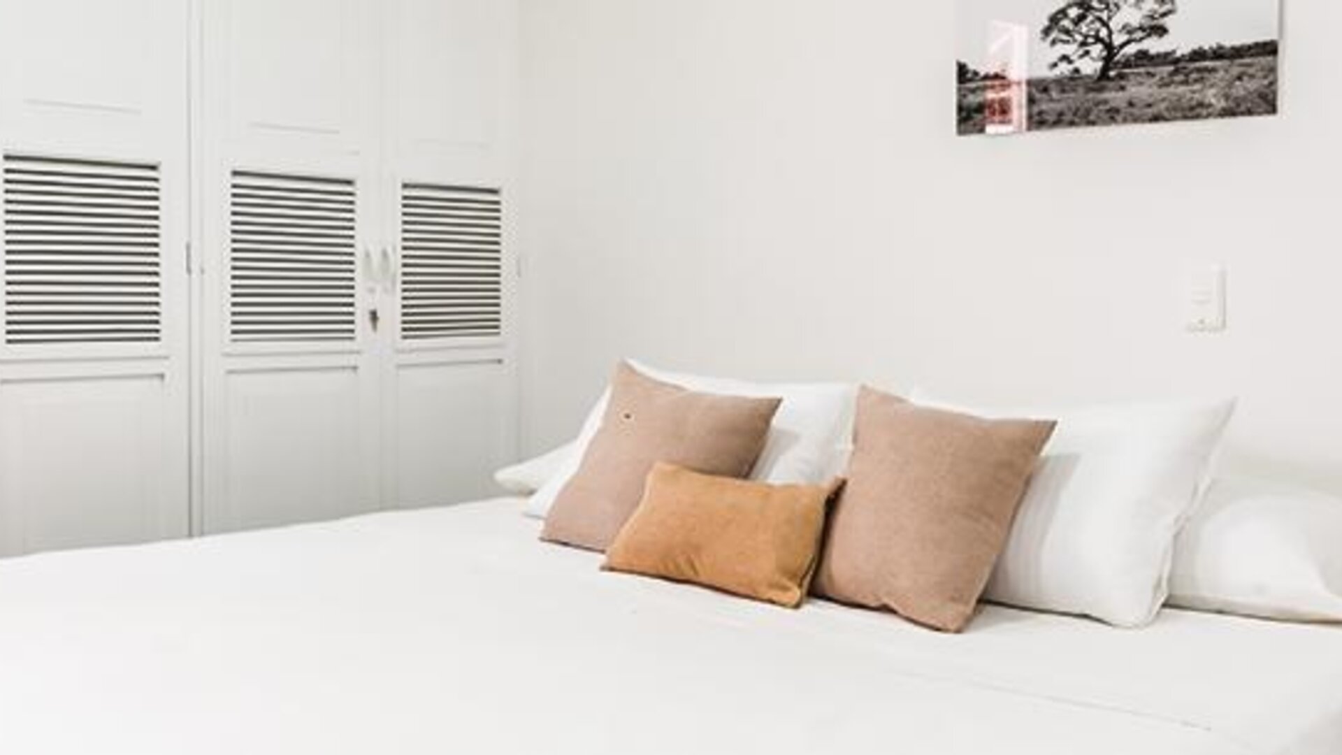 Guest room with large bed, neutral cushions, white wardrobes, and minimalist décor at Múcura Hotel & Spa.
