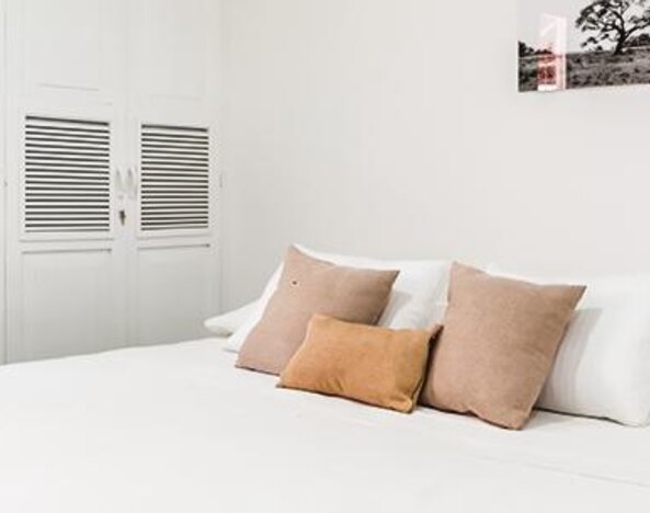 Guest room with large bed, neutral cushions, white wardrobes, and minimalist décor at Múcura Hotel & Spa.