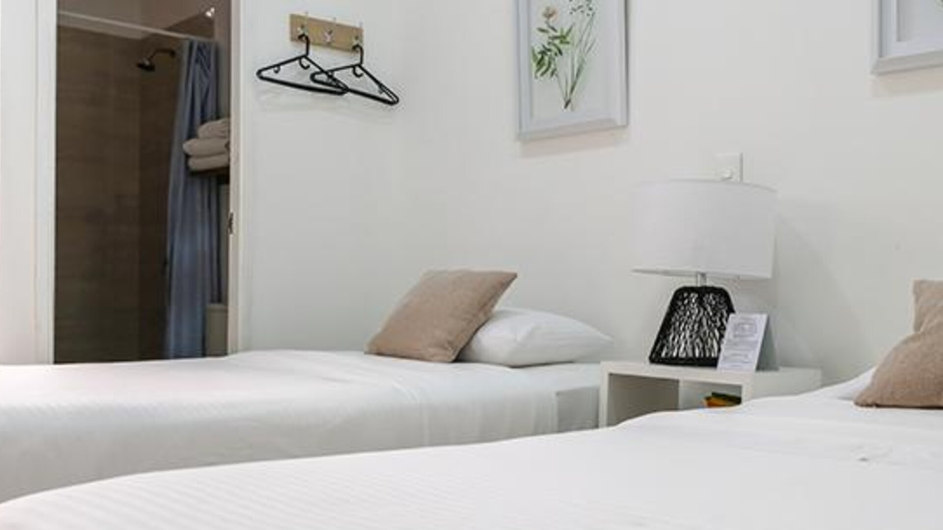 Guest room with two single beds, neutral décor, bedside lamp, and open bathroom area at Múcura Hotel & Spa.