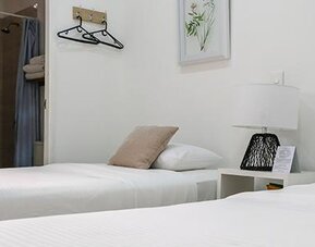 Guest room with two single beds, neutral décor, bedside lamp, and open bathroom area at Múcura Hotel & Spa.