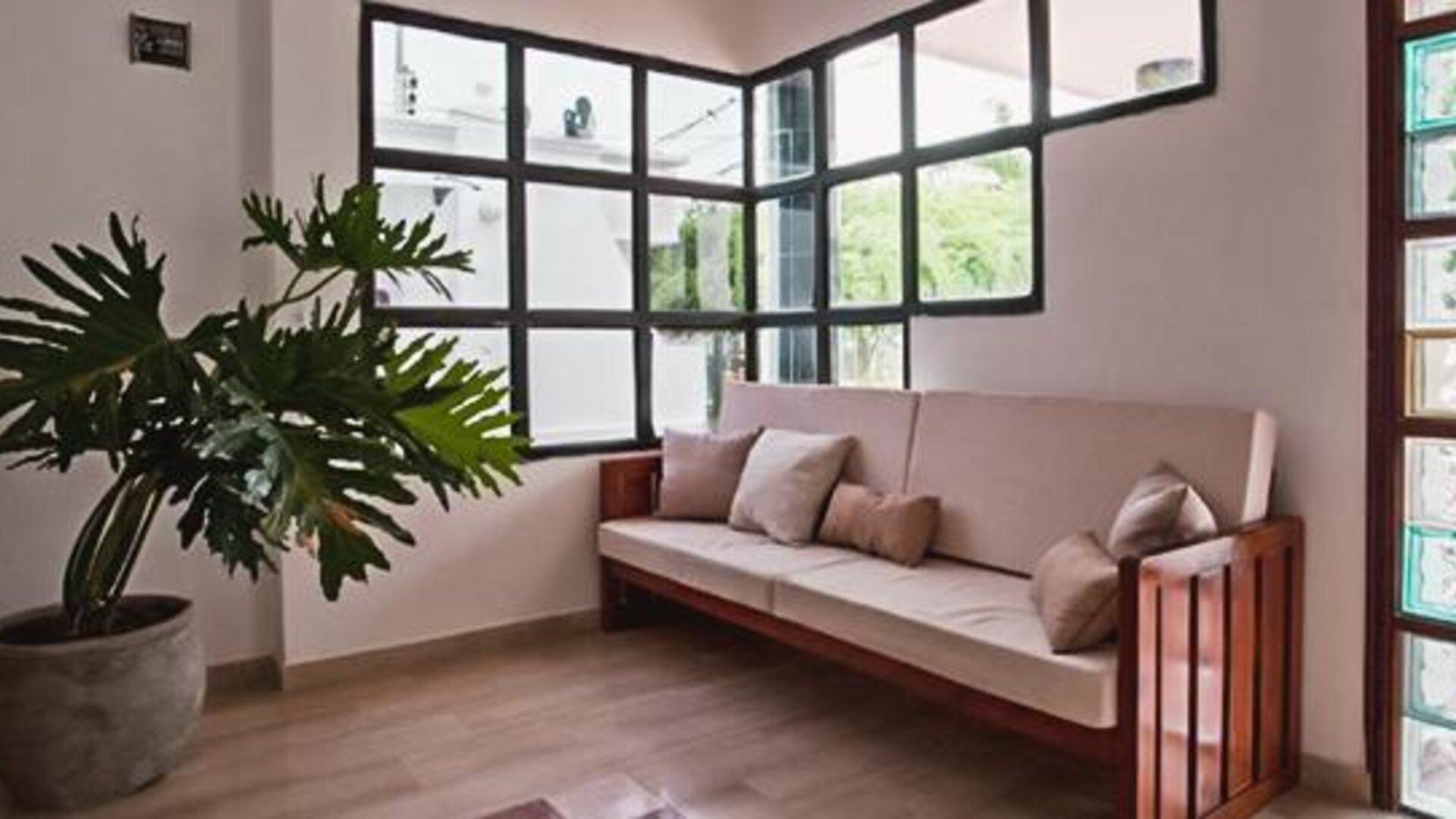 Bright lounge area with cushioned wooden bench, large windows, and indoor plant at Múcura Hotel & Spa.