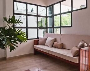 Bright lounge area with cushioned wooden bench, large windows, and indoor plant at Múcura Hotel & Spa.