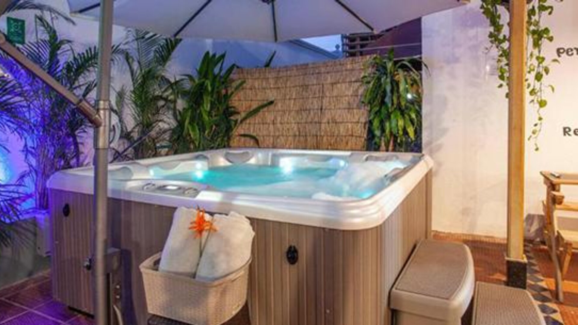 Outdoor hot tub surrounded by tropical plants, seating, and ambient lighting at Múcura Hotel & Spa.