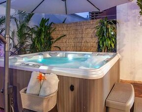 Outdoor hot tub surrounded by tropical plants, seating, and ambient lighting at Múcura Hotel & Spa.