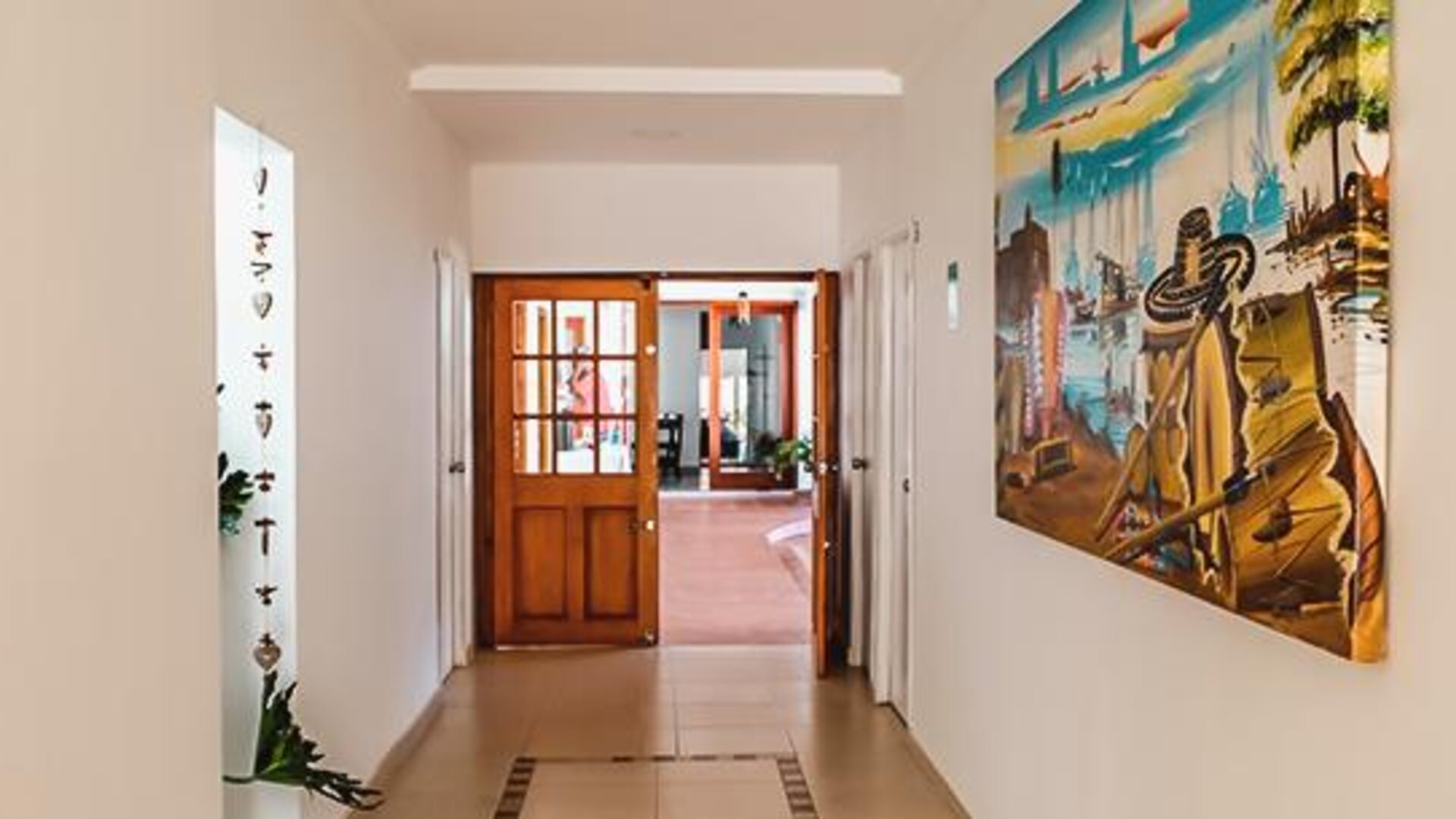 Bright hotel corridor with artwork and wooden doors leading to a common area at Múcura Hotel & Spa.
