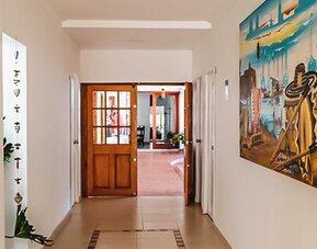 Bright hotel corridor with artwork and wooden doors leading to a common area at Múcura Hotel & Spa.