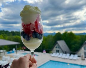 Dessert parfait with berries and whipped cream overlooking the outdoor pool and mountain scenery at SKYLARANNA Resort & Spa.