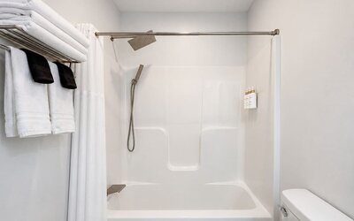 Guest bathroom featuring a bathtub and shower combination, modern shower fixtures, and neatly arranged towels at SKYLARANNA Resort & Spa.