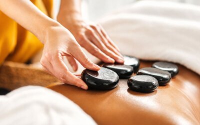Hot stone massage treatment featuring heated stones placed along a guest's back at SKYLARANNA Resort & Spa.