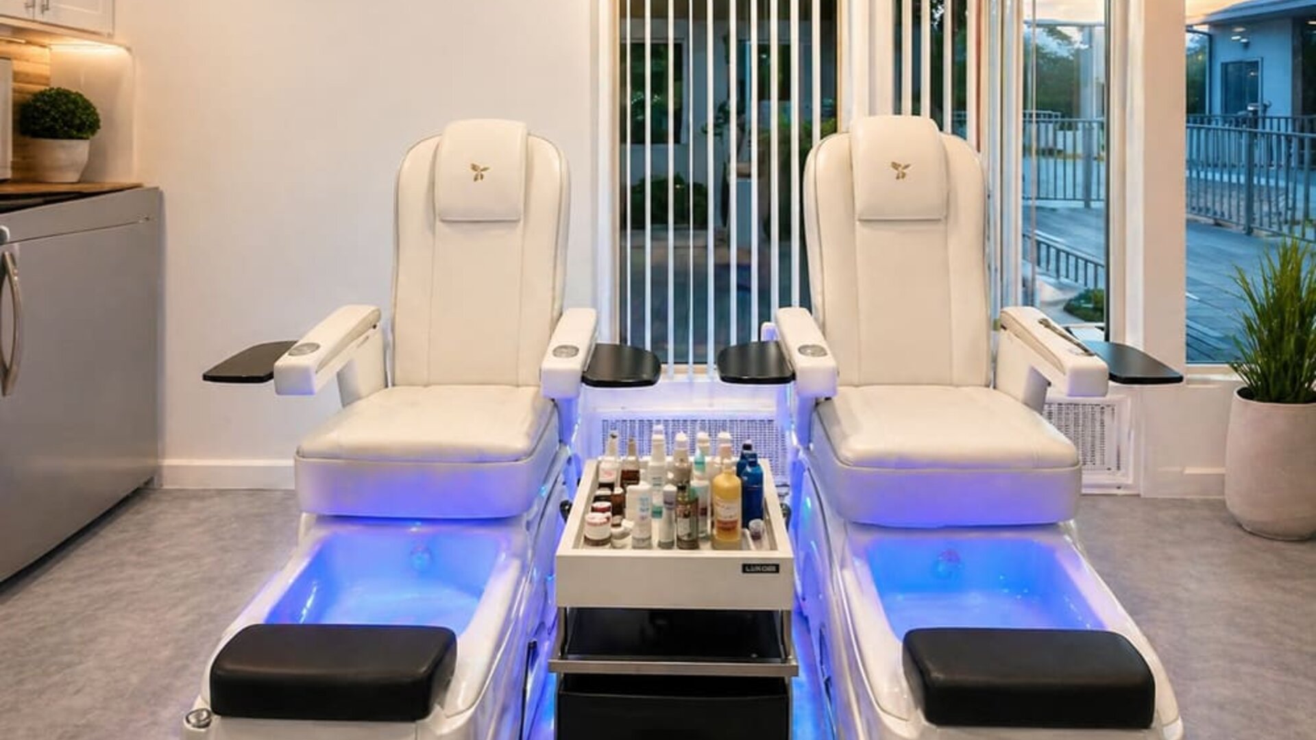 Spa area featuring two modern treatment chairs, foot basins, treatment products, and large windows at SKYLARANNA Resort & Spa.