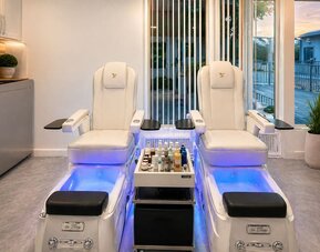 Spa area featuring two modern treatment chairs, foot basins, treatment products, and large windows at SKYLARANNA Resort & Spa.