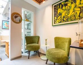 Welcoming common area featuring green lounge chairs, colourful artwork, and a guest refreshment station at Casa Anzures Suites.