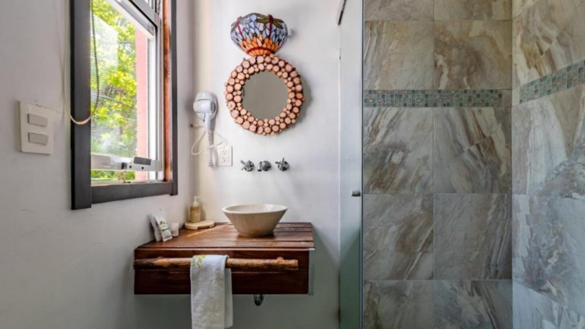 Guest bathroom featuring a vessel sink, wooden vanity, decorative mirror, natural light, and a tiled walk-in shower at Casa Anzures Suites.