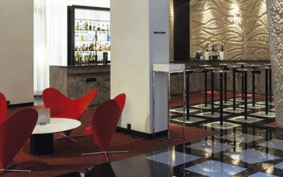 Contemporary bar and lounge featuring vibrant red seating, high-top bar stools, and a well-stocked bar at Hilton Madrid Aeropuerto.
