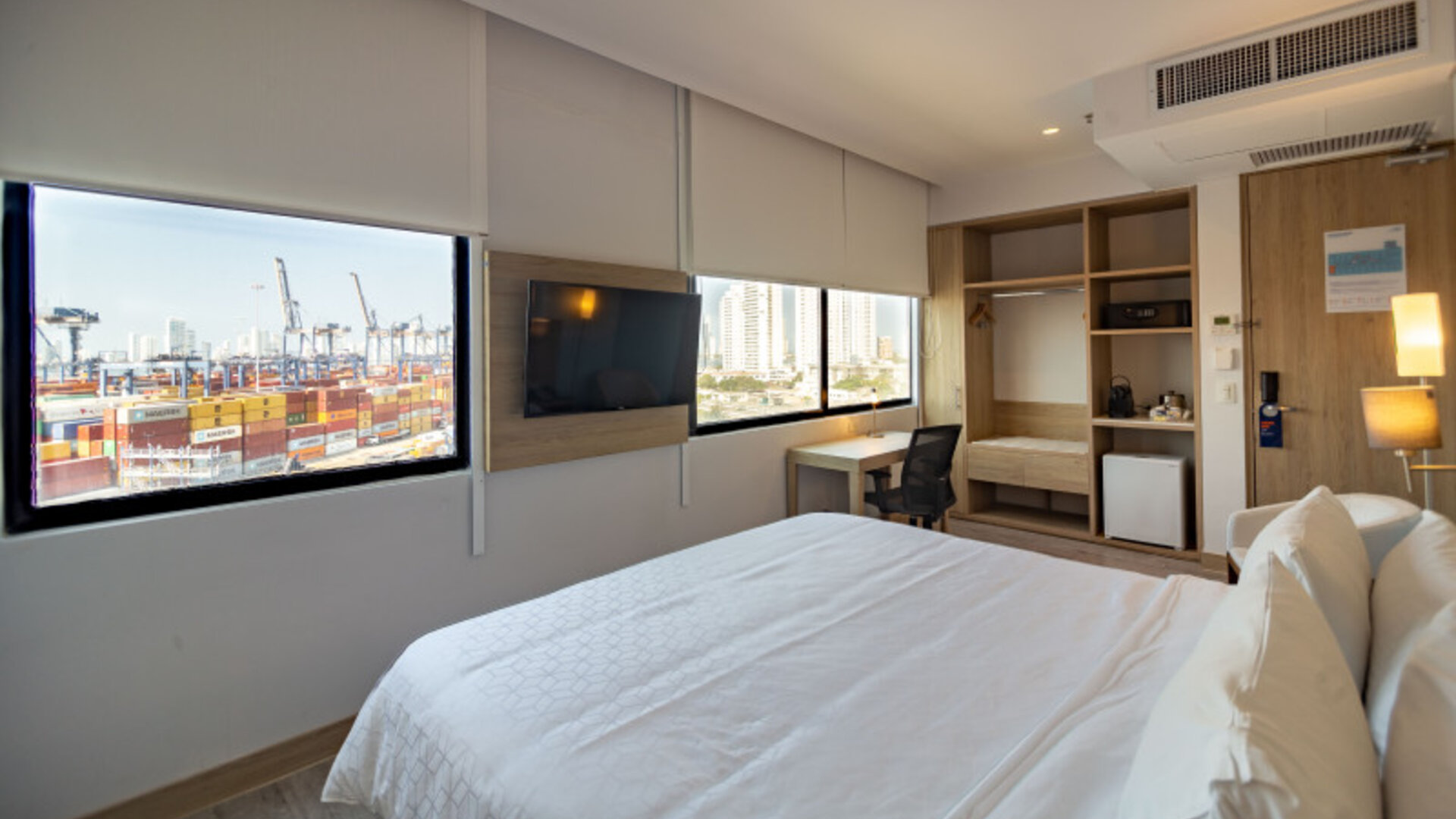 Bright guest room featuring a large bed, television, workspace, storage area, and views of the port at Holiday Inn Express Cartagena Manga.