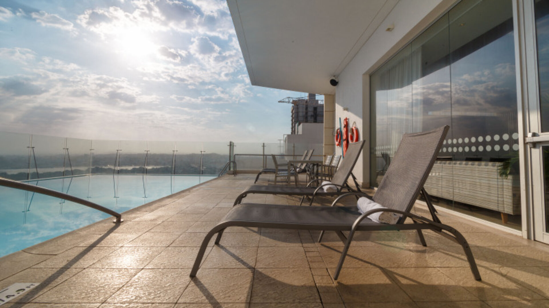 Rooftop pool deck featuring sun loungers, glass railings, and expansive views at Holiday Inn Express Cartagena Manga.