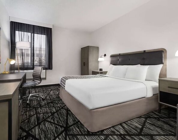 Comfortable guest room featuring a king bed, dedicated work desk, television, wardrobe, and contemporary décor at La Quinta Inn & Suites By Wyndham Cleveland Airport West.