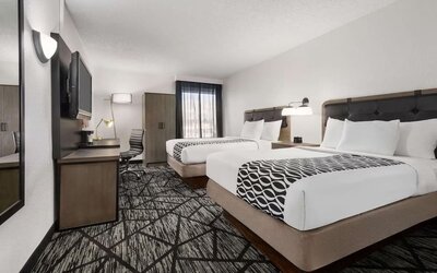 Comfortable guest room featuring two beds, a work desk, television, wardrobe, and modern furnishings at La Quinta Inn & Suites By Wyndham Cleveland Airport West.