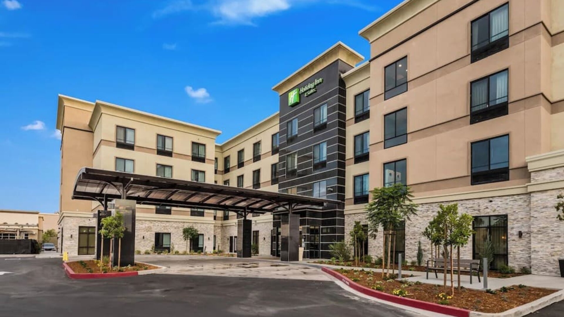 Exterior view of Holiday Inn & Suites Silicon Valley - Milpitas featuring the modern hotel building and covered entrance.