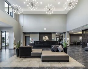 Modern hotel lobby featuring a reception desk, stylish seating, decorative lighting, and an open layout at Holiday Inn & Suites Silicon Valley - Milpitas.