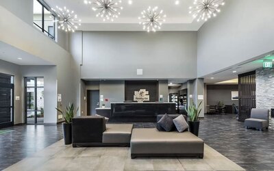 Modern hotel lobby featuring a reception desk, stylish seating, decorative lighting, and an open layout at Holiday Inn & Suites Silicon Valley - Milpitas.