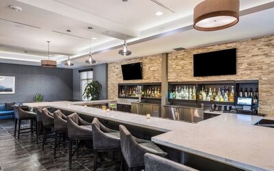 Contemporary hotel bar featuring a spacious counter, comfortable bar seating, televisions, and a selection of beverages at Holiday Inn & Suites Silicon Valley - Milpitas.