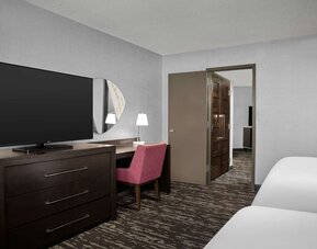 Comfortable guest room featuring two beds, a large television, desk and chair, and contemporary furnishings at Embassy Suites by Hilton Crystal City National Airport.