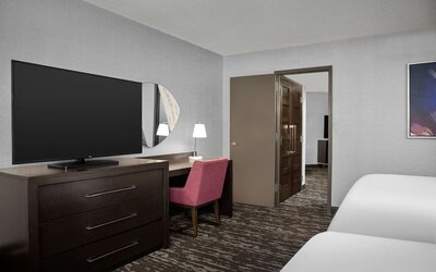 Comfortable guest room featuring two beds, a large television, desk and chair, and contemporary furnishings at Embassy Suites by Hilton Crystal City National Airport.