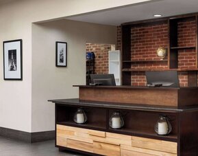 Contemporary reception desk featuring warm wood finishes, exposed brick accents, and modern décor at Wyndham Garden Pittsburgh Airport.