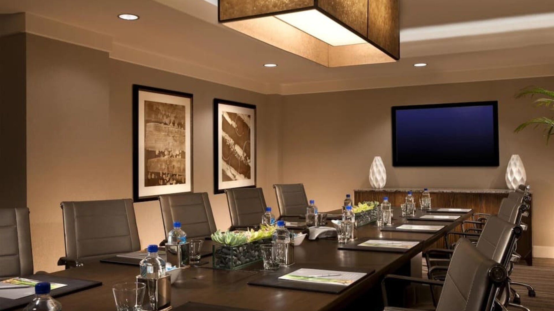 Professional meeting room with glasses of water and writing pads with pictures on the wall. 