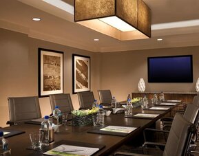 Professional meeting room with glasses of water and writing pads with pictures on the wall. 