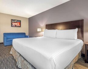 Comfortable king guest room featuring a large bed, blue sofa, bedside lighting, and contemporary décor. Best Western McCarran Inn.