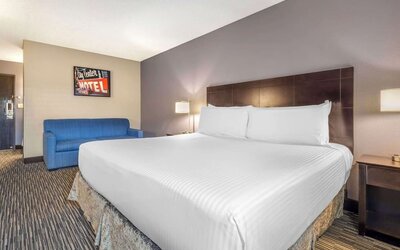 Comfortable king guest room featuring a large bed, blue sofa, bedside lighting, and contemporary décor. Best Western McCarran Inn.