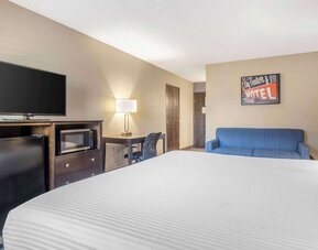 Guest room featuring a bed, blue sofa, television, mini fridge, microwave, and workspace. Best Western McCarran Inn.