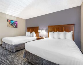 Guest room featuring two beds with wooden headboards, bedside lighting, and colourful wall art. Best Western McCarran Inn.