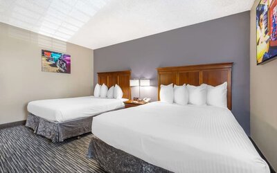 Guest room featuring two beds with wooden headboards, bedside lighting, and colourful wall art. Best Western McCarran Inn.
