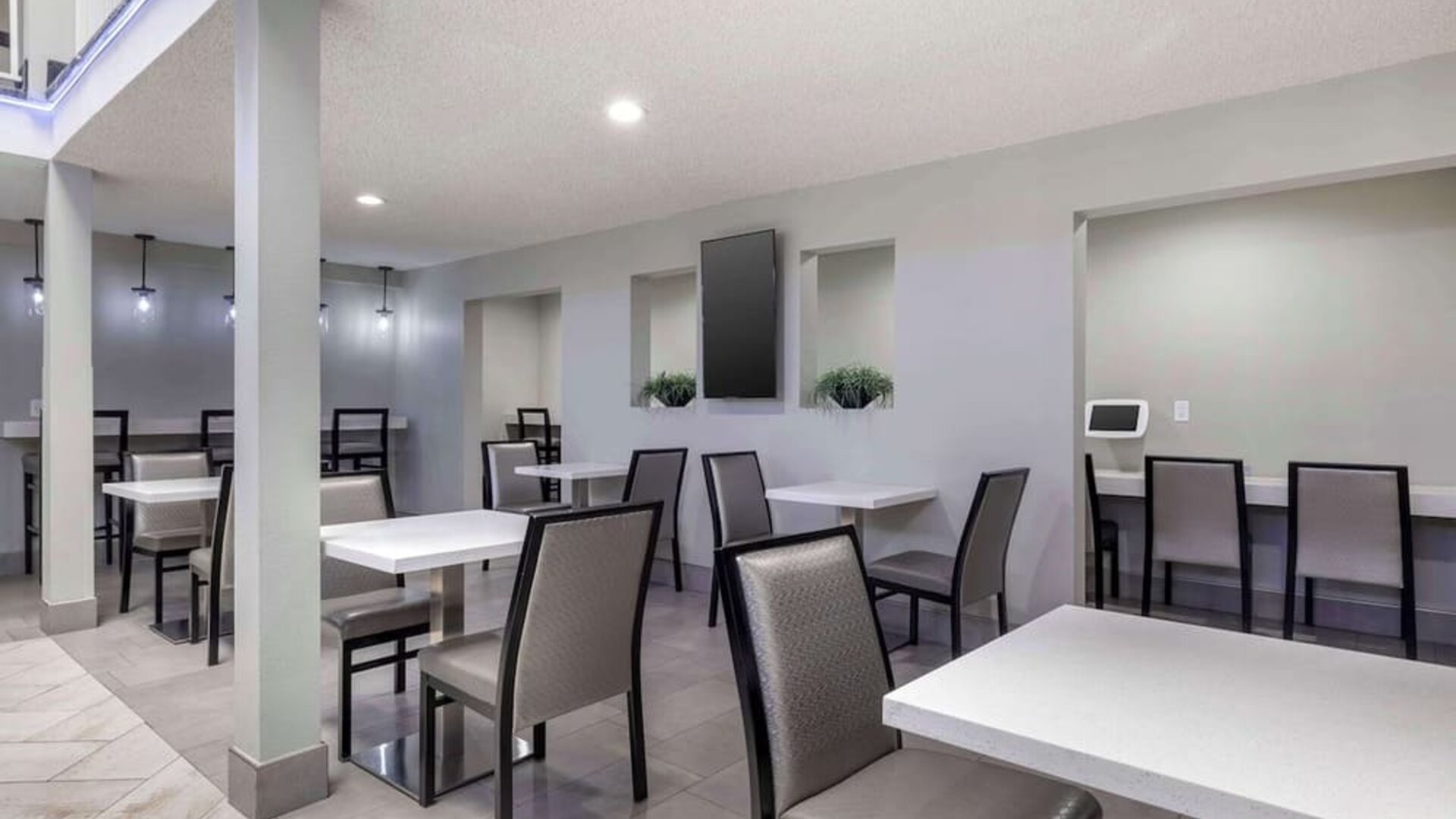 Modern dining area featuring multiple tables, comfortable chairs, counter seating, and bright overhead lighting. Best Western McCarran Inn.