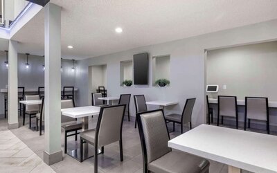 Modern dining area featuring multiple tables, comfortable chairs, counter seating, and bright overhead lighting. Best Western McCarran Inn.