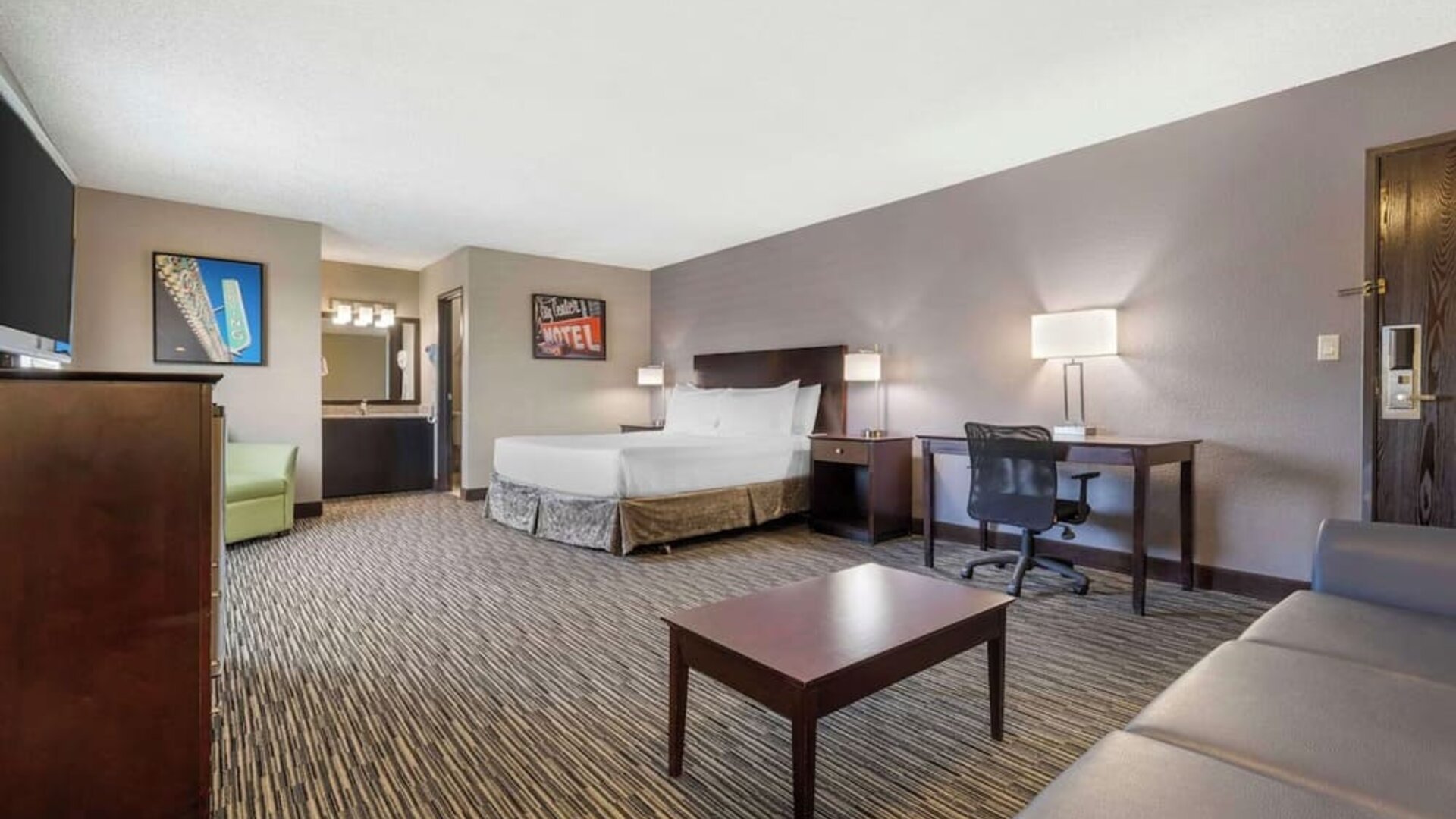 Spacious guest room featuring a bed, sofa, coffee table, workspace, and separate vanity area. Best Western McCarran Inn.