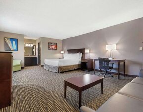 Spacious guest room featuring a bed, sofa, coffee table, workspace, and separate vanity area. Best Western McCarran Inn.