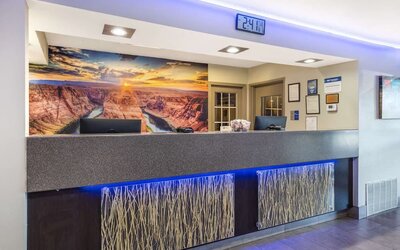 Reception desk featuring contemporary lighting, computer stations, decorative panels, and a scenic canyon mural. Best Western McCarran Inn.