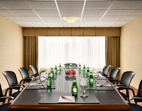 Boardroom featuring a long conference table, office chairs, bottled water, glasses, and writing pads. Crowne Plaza Englewood.