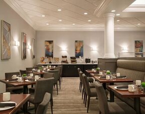 Dining area featuring set tables, upholstered seating, buffet station, and contemporary wall art. Crowne Plaza Englewood.
