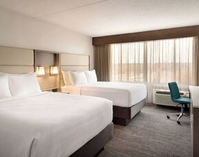 Guest room featuring two beds, large window, workspace, television, and contemporary furnishings. Crowne Plaza Englewood.