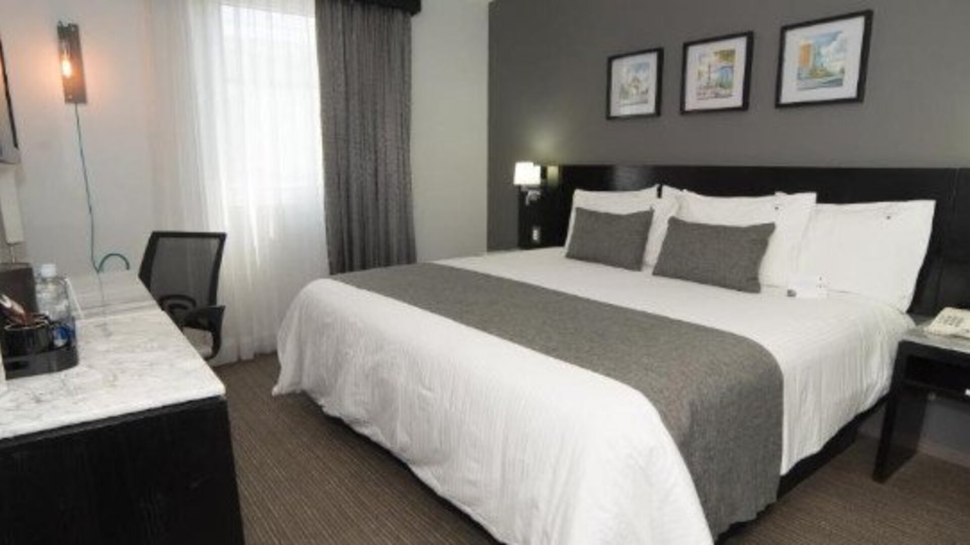 Guest room featuring a king bed, work desk, bedside lighting and modern neutral décor. LaiLa Hotel CDMX.