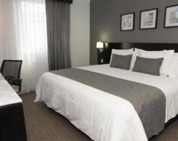 Guest room featuring a king bed, work desk, bedside lighting and modern neutral décor. LaiLa Hotel CDMX.