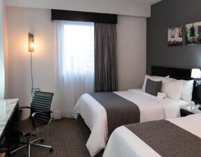 Guest room featuring two beds, a work desk, flat-screen TV and contemporary décor. LaiLa Hotel CDMX.